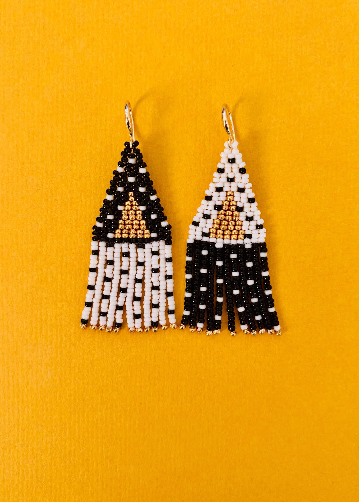 zwart witte polkadot oorbellen met een gouden driehoek middenin. gemaakt van kleine glaskralen.